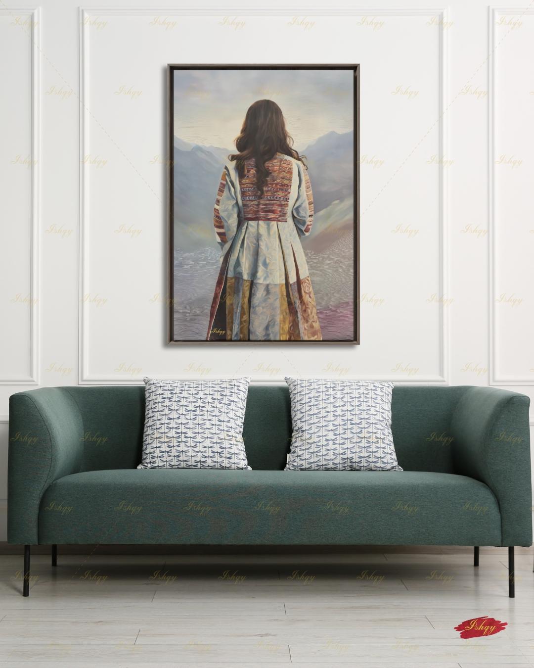 Back-view portrait of a woman with long dark wavy hair wearing a traditional Afghan embroidered dress with intricately paneled fabric in blue, rust, and earth tones, against a misty layered mountain landscape.