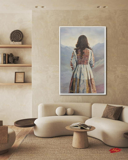 Back-view portrait of a woman with long dark wavy hair wearing a traditional Afghan embroidered dress with intricately paneled fabric in blue, rust, and earth tones, against a misty layered mountain landscape.